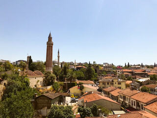 view of the city from above. houses with brown, brick roof. life in a tropical, warm country. travel to the sea, vacation. on the square stands a tower with a sharp spire