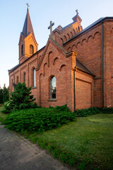 Fototapeta na wymiar Church of St. John the Baptist in the village of Opsa, Belarus. Neo-Gothic church made of red brick with one bell tower and low symmetrical sacristy.