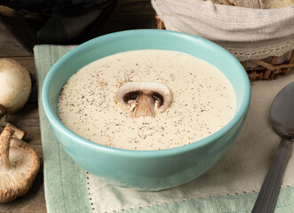 Mushroom soup in a bowl with bread slices and wine over wooden table