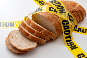 Sliced bread and yellow caution tape isolated on white background concept for food insecurity,...