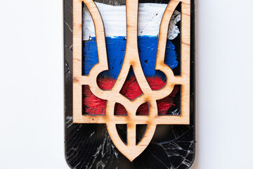 The wooden coat of arms of Ukraine lies on the painted flag of Russia on a white background, Ukraine and Russia, war 2022