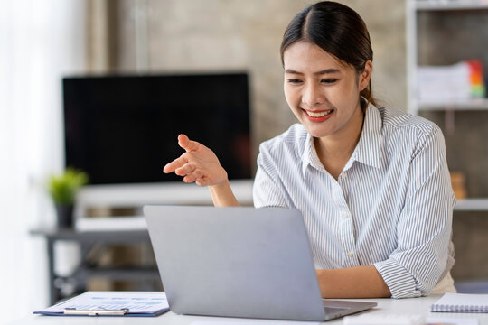 Portrait of Asian businesswoman with laptop Makes video calls and online meetings with colleagues at her office. Young woman working on a laptop in the office.