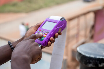 closeup shot of a African man putting his pin in a payment terminal after shopping