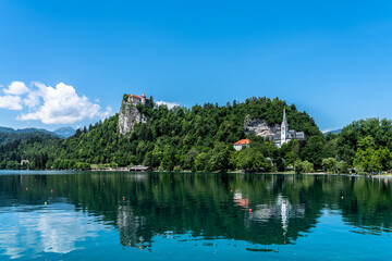 Fototapeta na wymiar Beautiful idyllic panorama view of Lake Bled with Bled Castle, St. Martin's Parish Church and Slovenian Alps in background on sunny summer day with blue sky cloud, Bled, Slovenia