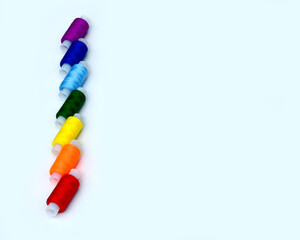 Spools of sewing thread of seven colors of the rainbow close-up on a light background