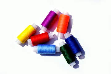 Spools of sewing thread of seven colors of the rainbow close-up on a light background