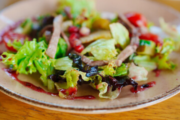plate with salad with meat, vegetables and red sauce. 