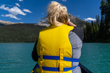 Blonde woman paddles on the front of a canoe on Emerald Lake in Yoho National Park, British...