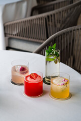 Four colorful summer cocktails in glasses on white table. Assortment of fresh summer drinks. Pink and red sangria cocktails, orange punch cocktail