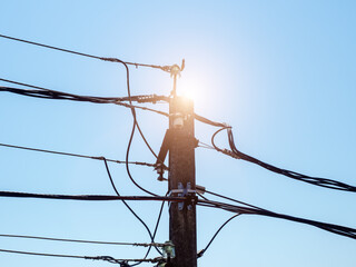 Electric pole backlit by the sun. Iron electric pole with wires with solar backlight against the...