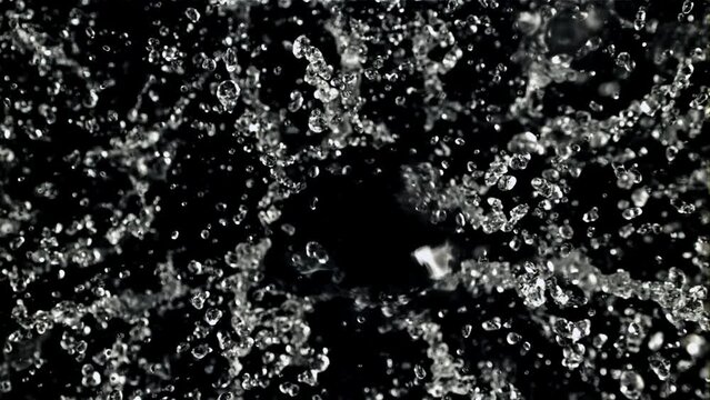 Splashes of water take off and rotate in flight. Top view. On a black background. Filmed on a high-speed camera at 1000 fps.