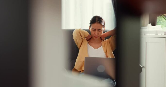 Young asia female girl or university student sit on sofa chair with computer laptop feel pain, hurt shoulder from hard work overtime in living room at home. Office syndrome, Work life balance concept.