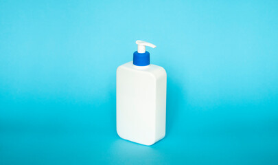 Liquid container for gel, lotion, cream, shampoo, bath foam. Cosmetic plastic bottle with dispenser pump on blue background. Cosmetic packaging mockup with copy space.