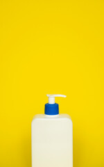 Liquid container for gel, lotion, cream, shampoo, bath foam. Cosmetic plastic bottle with dispenser pump on yellow background. Cosmetic packaging mockup with copy space.