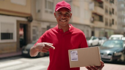 Young latin man delivery worker pointing with finger to package at street