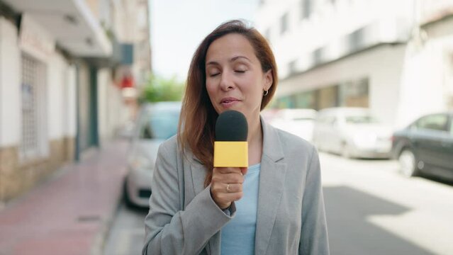 Young woman reporter working using microphone at street