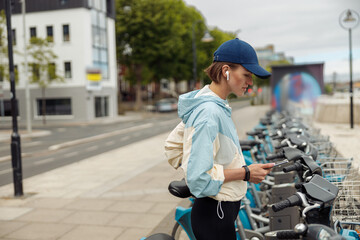 Young sportive woman renting bicycle in bike sharing city service
