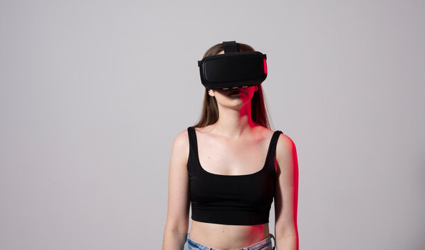 Happy young woman playing on VR glasses. Virtual reality concept with young girl having fun in virtual reality goggles. Metaverse.