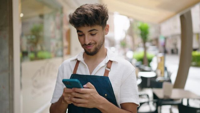 Young arab man waiter using smartphone working at restaurant