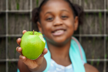 african school girl with backpack, eating green apple