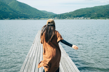 湖の桟橋で走る女性キャンパー（キャンプ場・アウトドア）
