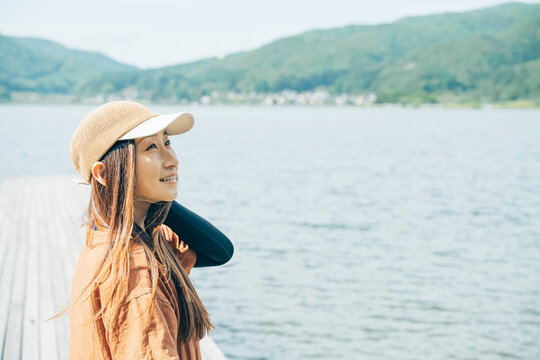湖の桟橋に立つ女性キャンパーの横顔（キャンプ場・アウトドア）
