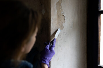 Female Expertise Removing Old Paint from the Wall with a Metal Spatula