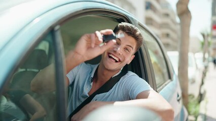Young hispanic man smiling confident holding key of new car at street