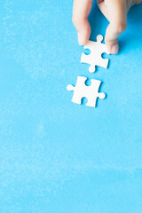 Close up hand holding and playing jigsaw game incomplete. White part of jigsaw puzzle pieces on...