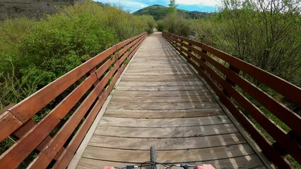 POV action camera perspective riding mountain bike on scenic wood bridge
