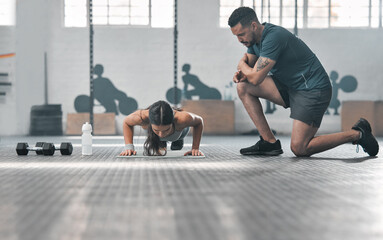 Fit and athletic woman training with her personal trainer at the gym. An active female athlete doing pushups with her coach for her morning workout routine at a fitness and exercise facility - obrazy, fototapety, plakaty