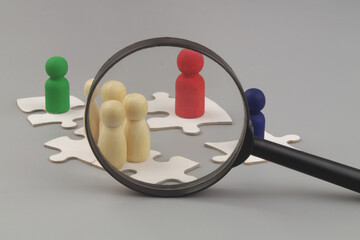 Cooperation and unity review. Colored people figures on puzzles under magnifying glass on gray...