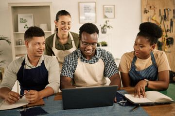 Fashion designers, colleagues and creatives browsing laptop while meeting to brainstorm a clothing range in a workshop. Team planning garment designs in a textile and manufacturing studio or factory