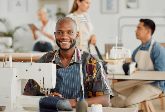 Fashion designer, young man and creative in a workshop stitching clothes. Portrait of a happy, smiling and cheerful factory worker at a sewing machine in a textile startup and manufacturing studio