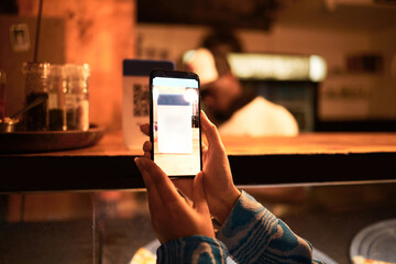 Person with phone camera scanning QR bar code for online menu at a modern restaurant, shop or cafe...