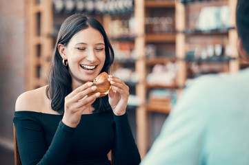 Happy, beautiful and relaxed woman eating on a date at a restaurant with her partner on the weekend. Young and attractive female enjoying a meal or breakfast burger at a cafe with her boyfriend