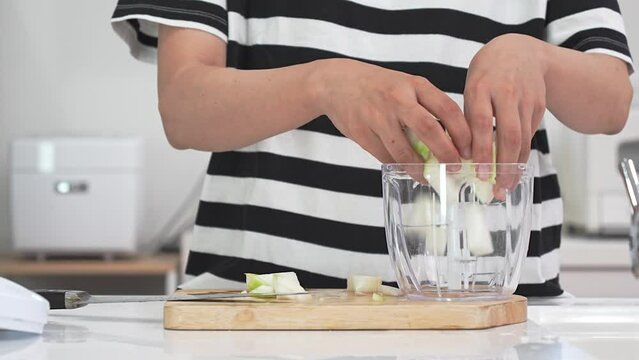 玉ねぎをみじん切りにする女性の手元