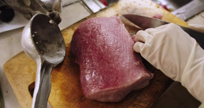 Close up of piece of tollo fish being cut with a knife into pieces to cook ceviche.