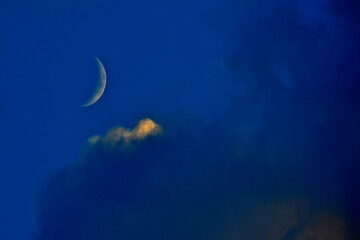 Waxing Crescent Moon and cloud partially lit by setting sun