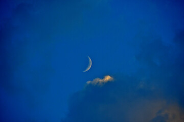 Waxing Crescent Moon at sunset with edge lit cloud in foreground 