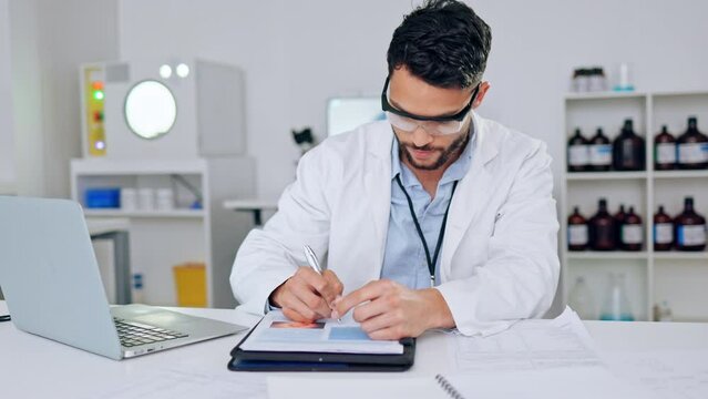 Happy, confident male scientist satisfied with science test results. Young intern writing and working on a computer with a smile in a laboratory. Portrait of a lab worker content with his success