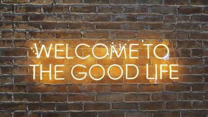 Cartel de neón naranja que dice "bienvenido a la buena vida" en el fondo de la pared de ladrillos, vista frontal