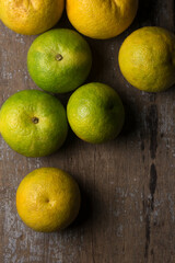 sweet orange fruits scattered on rustic wooden table top, taken directly from above with space for text