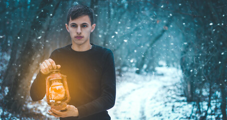 A man with a kerosene lamp in his hand walks through a snowy forest at night, a photo banner with a place for an inscription