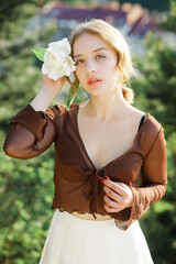Close-up portrait of a cute blonde with a white flower in her hand. Vintage tone..Soft blur...