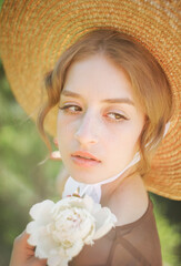 Close-up portrait of a cute blonde in a straw hat at sunset. Vintage tone..Soft blur background