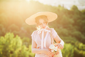 Close up portrait of a sweet blonde in a straw hat at the sunset