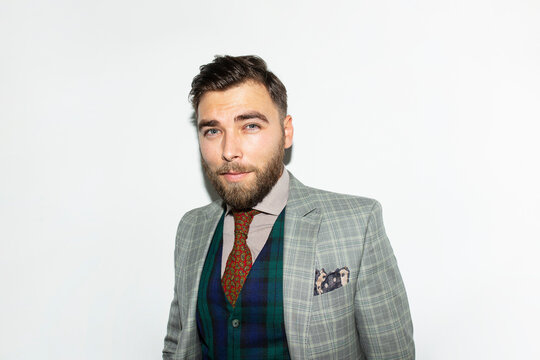 Front image of a confident male beard in an elegant classical suit, over white background, looking at camera.