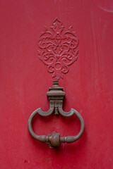 Closeup view of antique door knocker on ancient red wooden door, Montpellier, France