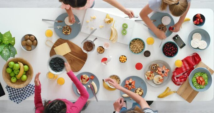 Fun, healthy and creative cooking for children using fresh, nutritious and organic food. Top view of young people using natural fruits, cereals and berries to make cute kids meals at home or school